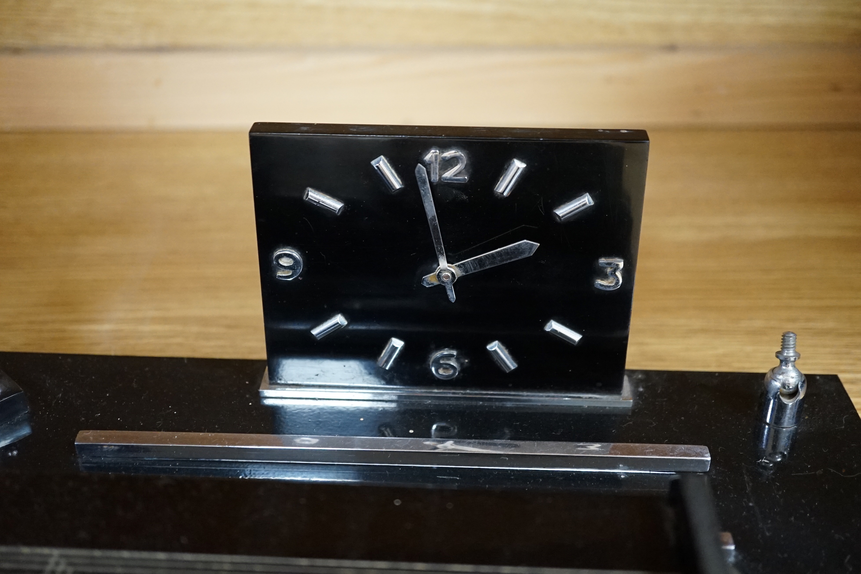 A black Bakelite box and similar clock desk stand, a faux marble clock, a marble clock, and a chrome box containing phenolic dominoes, desk stand 36cm wide (5)